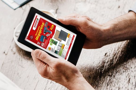 Eine Person schaut sich einen Online-Prospekt eines Baumarktes auf einem Tablet an.